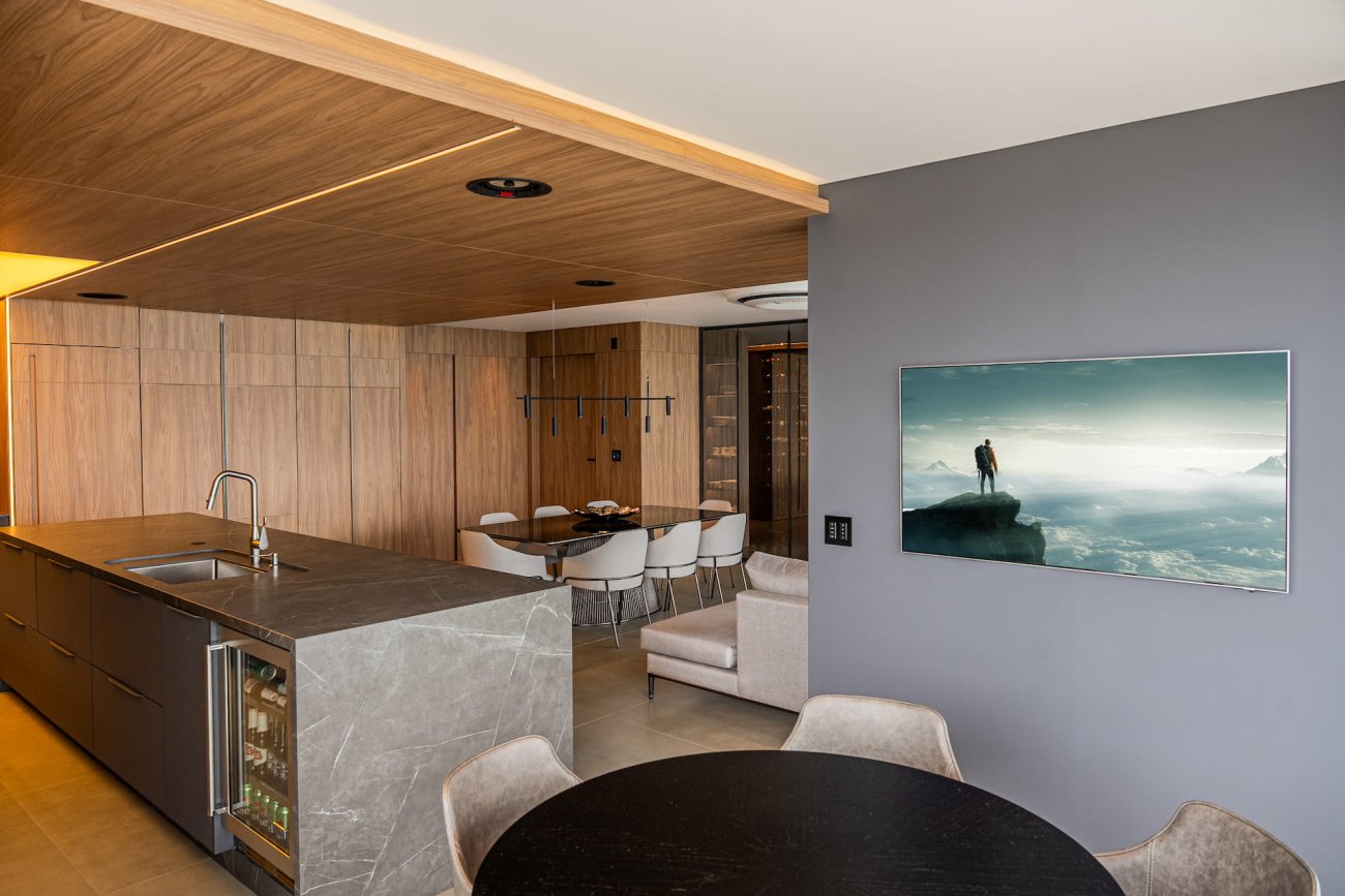 No living, o coração do apartamento, os moradores podem aproveitar um sistema de áudio de alta fidelidade, com a excelência, potência e clareza sonora das caixas de som Focal e do subwoofer Paradigm. Como ressaltou a arquiteta Polyana Karine Franco, a alta qualidade acústica foi uma demanda dos proprietários: "Para complementar o projeto de interiores, os clientes buscaram por qualidade sonora, atributos de imagem, capacidade dos equipamentos e tecnologia empregada. Esta integração entre os sistemas confere a eles uma experiência completa, facilitadora de processos e auxiliar a uma vivência de conforto".